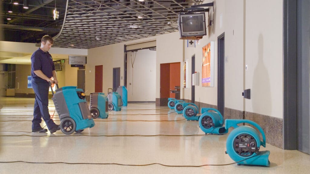 A certified technician from Omaha Water Restoration setting up turbo drying fans and dehumidifiers in the lobby of a commercial business located in Bellevue, NE.