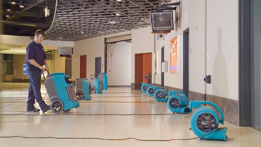 A certified technician from Omaha Water Restoration is setting up turbo drying fans and dehumidifiers in the lobby of a commercial establishment located in Omaha, NE.