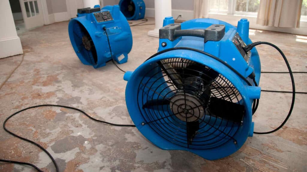 Three large blue fans set up by Omaha Water Restoration to dry a home damaged by water in Bennington, NE.