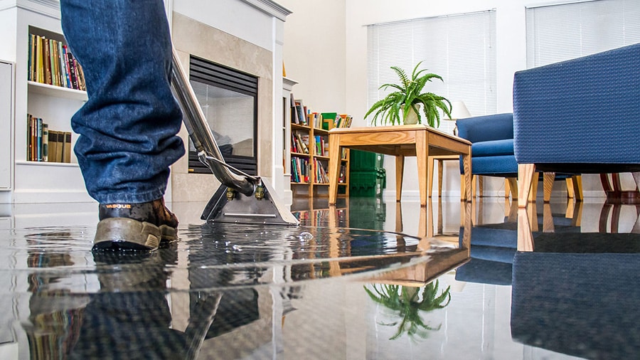 A certified technician from Omaha Water Restoration is extracting standing water from a home in Omaha, NE, using a powerful water extractor.